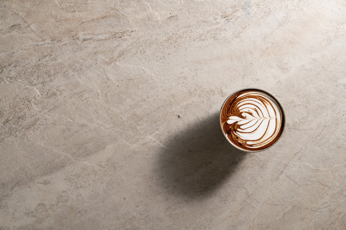 A warm milk drink in a glass, seen from above on a pale stone surface