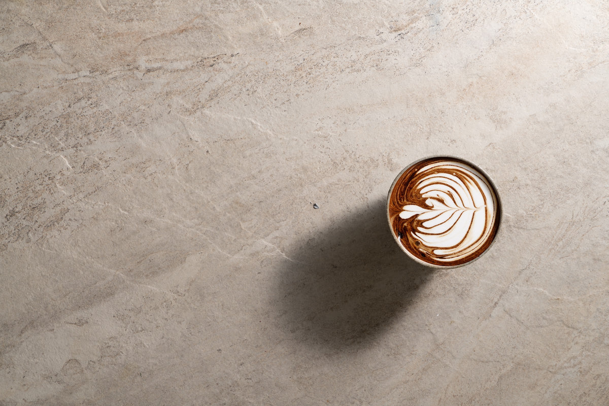 A warm milk drink in a glass, seen from above on a pale stone surface