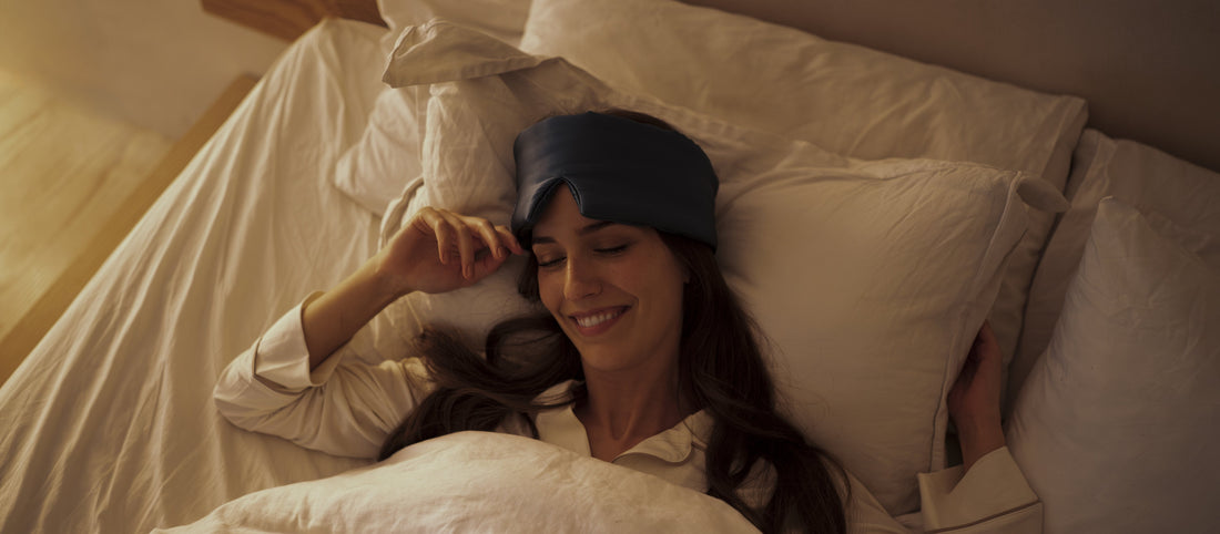 Woman resting in bed wearing the Sweet Bee Deep Sleep Eye Mask in warm evening light