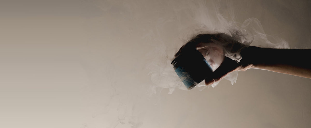 A hand holding the open Breathe Deep Cloud Balm jar with vapour rising