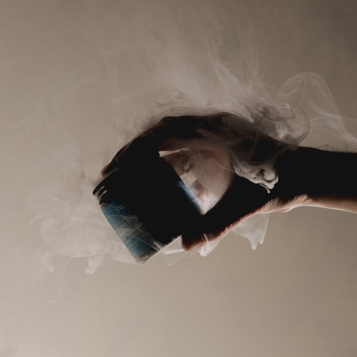 A hand holding the open Breathe Deep Cloud Balm jar with vapour rising