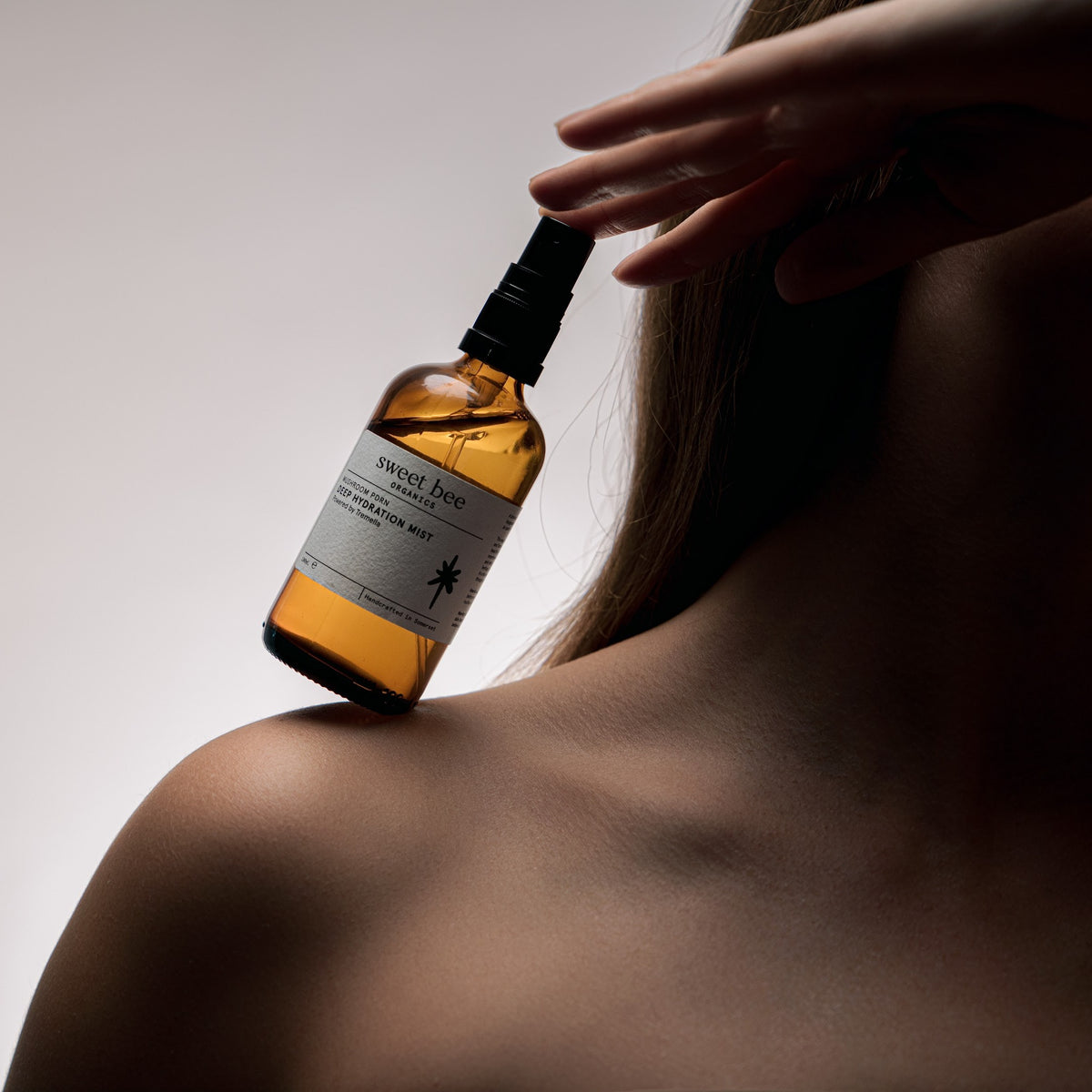 Deep Hydration Mist held at the shoulder, fine mist spray head in view