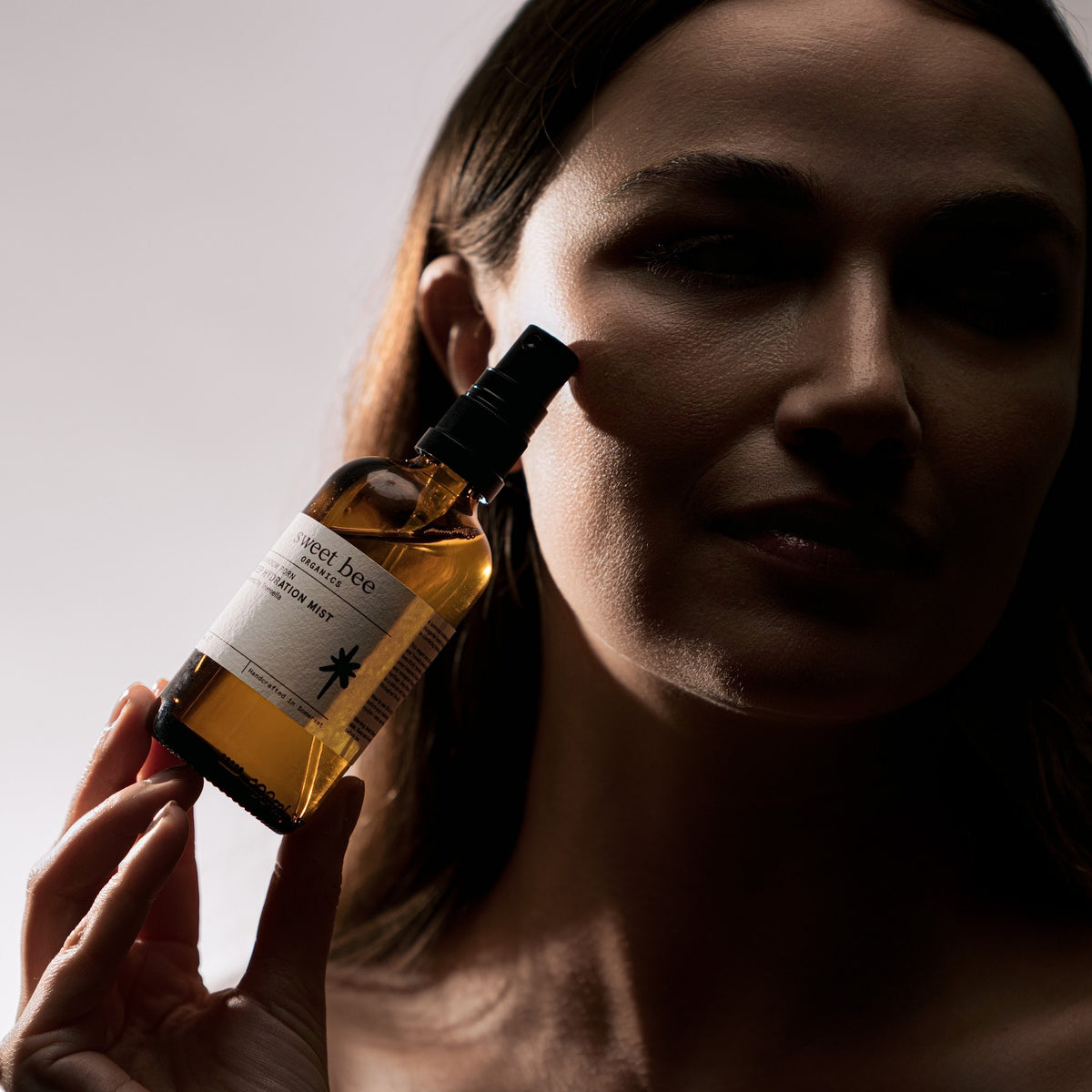 A woman holding Deep Hydration Mist beside her face
